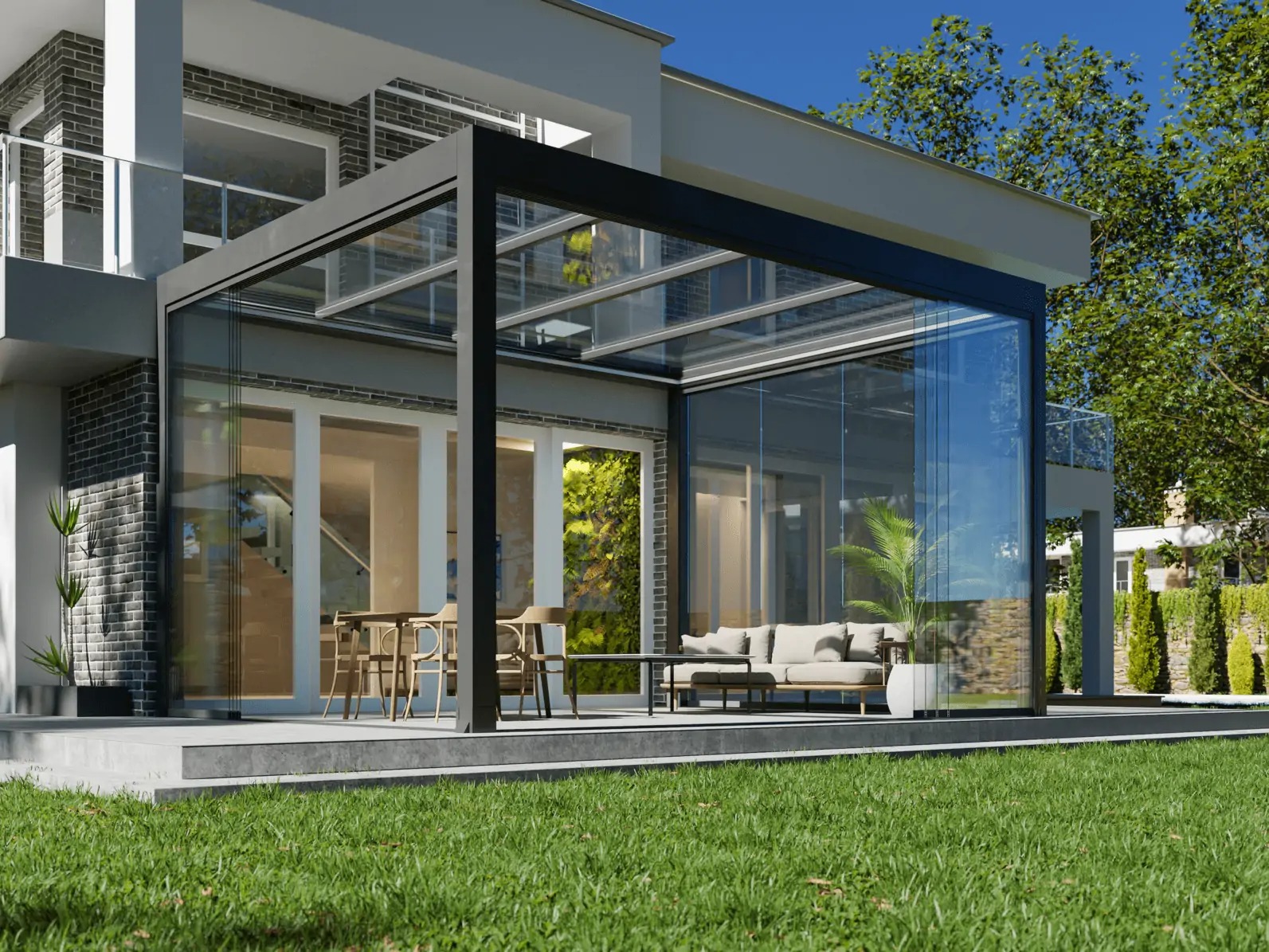 Nowoczesna zabudowa tarasu z przeszklonymi ścianami i czarną ramą, widok z zewnątrz na meble ogrodowe i zieloną ścianę, trawnik na pierwszym planie.