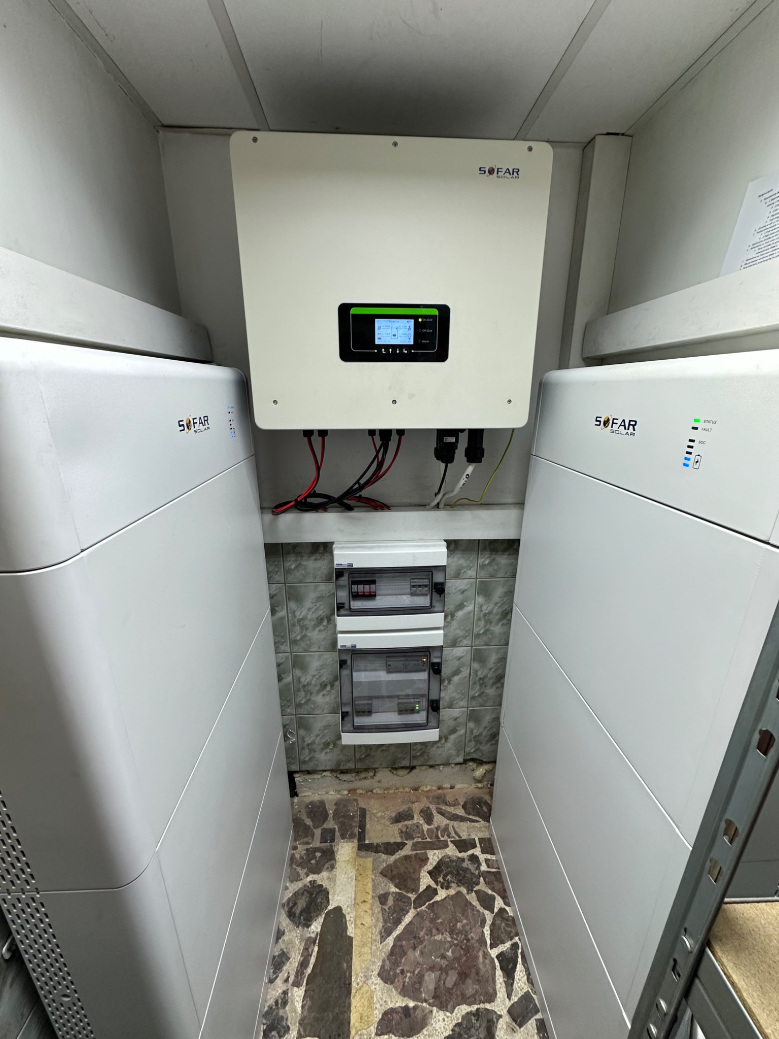 Instalacja wewnętrzna z dwoma białymi magazynami energii i inwerterem marki Sofar Solar, z widoczną rozdzielnicą elektryczną na tle ściany wyłożonej płytkami.