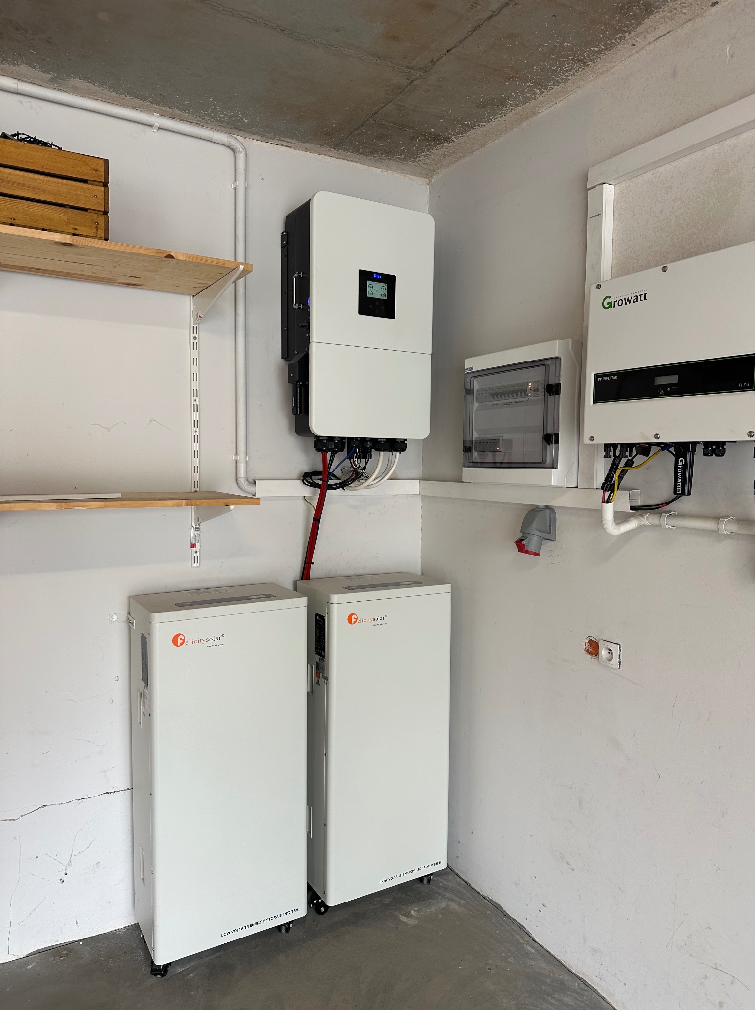 Kompletna instalacja magazynu energii z dwoma akumulatorami Felicity Solar, inwerterem i rozdzielnicą, zamontowana w pomieszczeniu technicznym. Widoczne okablowanie i elementy montażowe.
