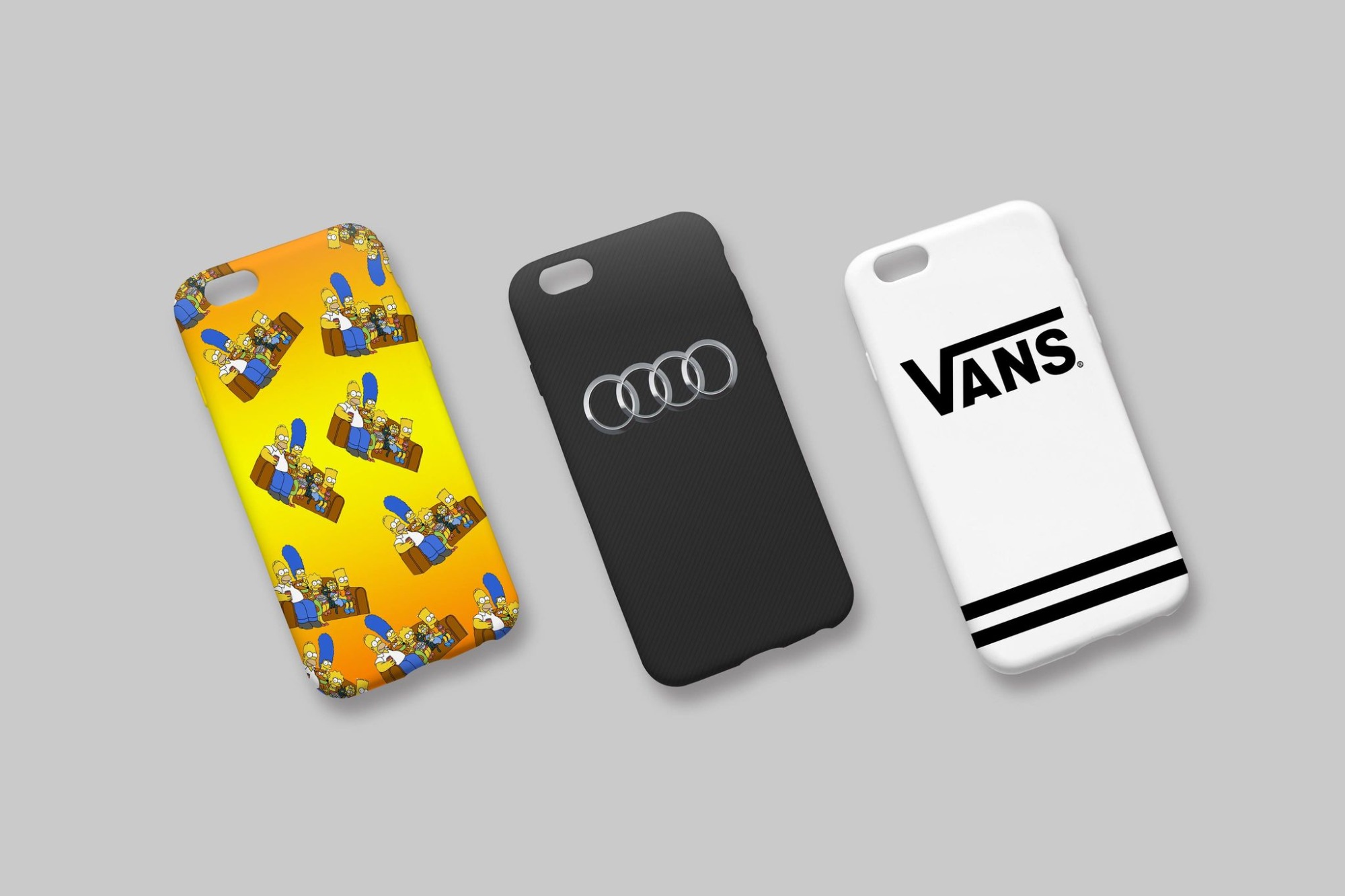 Trzy etui na telefon leżące obok siebie: żółte z motywem Simpsonów, czarne z logo Audi i białe z logo Vans.