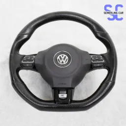 Czarna, skórzana kierownica samochodowa Volkswagen R z perforowaną skórą, przyciskami funkcyjnymi i srebrnym logo VW na tle jasnej powierzchni.