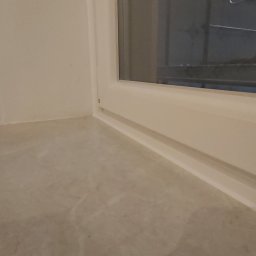 Wingedas - Fragment białego okna z widocznym parapetem o marmurkowej fakturze i częścią zewnętrznej konstrukcji za szybą.