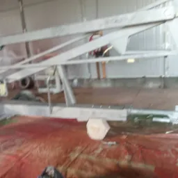 Metalowa konstrukcja po obróbce, zabezpieczona podkładem, widoczna w warsztacie, na podłodze resztki obróbki i zabezpieczenia.