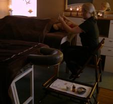 Kobieta wykonuje cosmolifting japoński na leżącej klientce w gabinecie, widoczne świece i buteleczki z olejkami.