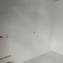 Wnętrze pomieszczenia po świeżo wykonanych pracach wykończeniowych, widoczne gładkie, białe ściany z przygotowanymi otworami na gniazdka elektryczne i włączniki.