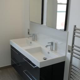 Dariusz Wysocki - Nowoczesna łazienka z podwójną umywalką nablatową, czarnymi szafkami z chromowanymi uchwytami, dwoma prostokątnymi lustrami z oświetleniem LED i grzejnikiem drabinkowym.