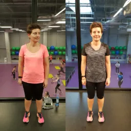 Kobieta prezentuje metamorfozę sylwetki, stojąc na tle sali fitness, widoczne zmiany w ubraniu i postawie, na podłodze leży ręcznik, telefon i butelka wody.