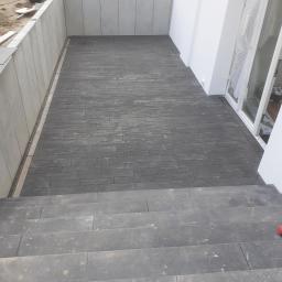 GmbH Krzysztof Fischer - Ułożona kostka brukowa na patio z niskimi schodami, widoczny odpływ liniowy przy ścianie budynku.