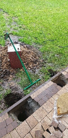 Wykop pod przydomową oczyszczalnię ścieków z widocznymi elementami konstrukcyjnymi i narzędziem do prac ziemnych na zewnątrz.