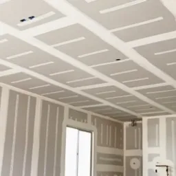 Poddasze w trakcie zabudowy płytami gipsowo-kartonowymi, widoczne profile konstrukcyjne i szpachlowane łączenia, przygotowane do dalszych prac wykończeniowych.