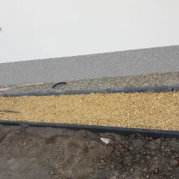 Przygotowanie podłoża pod elewację w Rybniku: widoczne warstwy izolacyjne, kamień ozdobny i obrzeża.