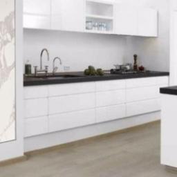 KAMEL Mariusz Kamela - Pionowy grzejnik panelowy z marmurowym wzorem w nowoczesnej, minimalistycznej kuchni z białymi szafkami i czarnym blatem.