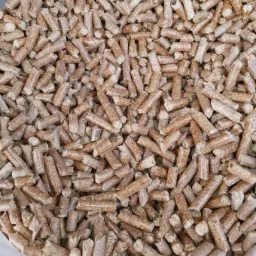 Jasnobrązowe granulki opału drzewnego, widoczne z bliska, wypełniające kadr.