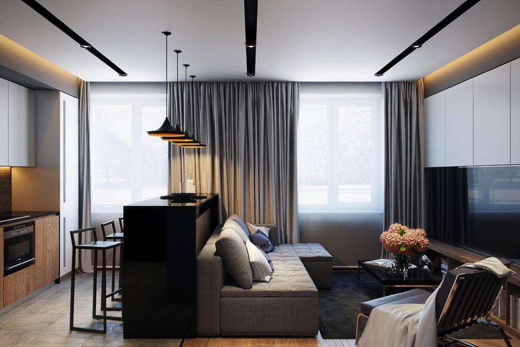 Nowoczesne wykończenie wnętrza salonu z aneksem kuchennym. Szara sofa, czarny barek, minimalistyczne lampy wiszące i subtelne oświetlenie sufitowe.