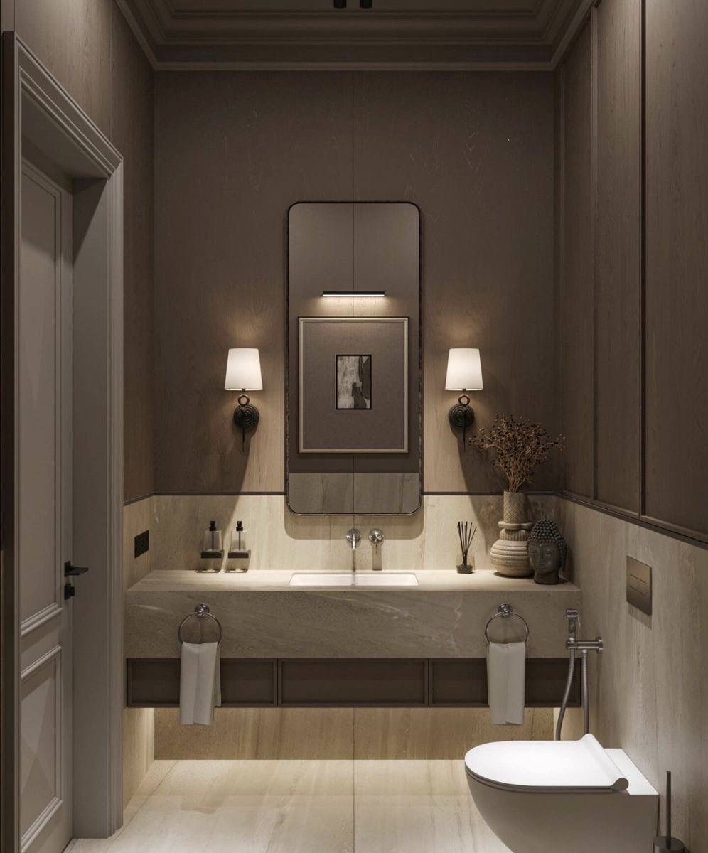 Elegancka łazienka w stonowanych barwach z marmurową umywalką, lustrem w czarnej ramie i dekoracyjnymi lampami ściennymi. Minimalistyczny design z akcentami dekoracyjnymi.