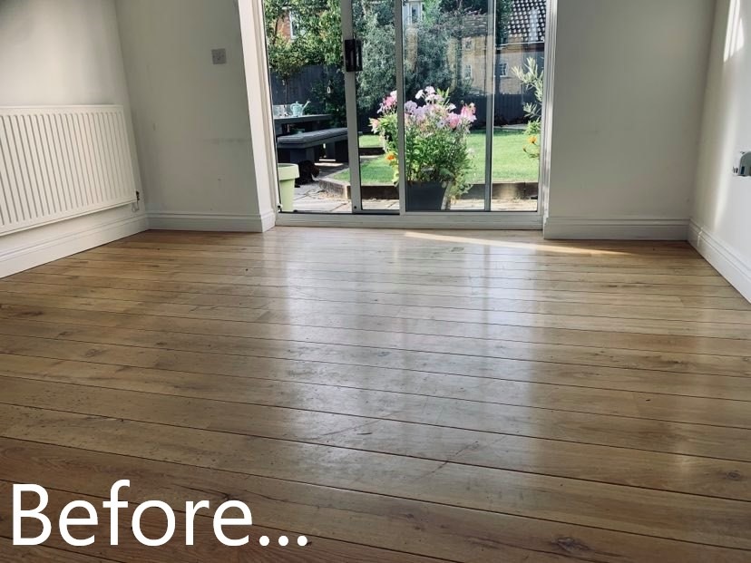 Jasna, drewniana podłoga w pokoju przed renowacją, widoczne ślady użytkowania i zarysowania, z napisem 'Before...' w dolnej części kadru, duże okno tarasowe z widokiem na ogród w tle.