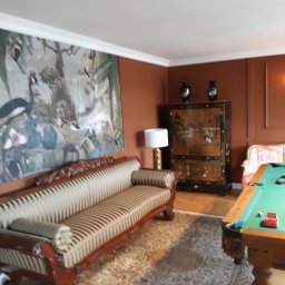 Renow Obrebski - Elegancki salon z antycznym kredensem, sofą w paski i stołem bilardowym, ściany pomalowane na ciepły, brązowy kolor.