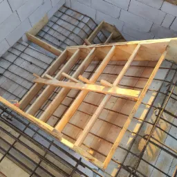 Konstrukcja szalunku z drewnianych belek i siatki zbrojeniowej na poddaszu w Tucholi, przygotowana do wylania betonu.