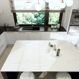 Wnętrze nowoczesnej kuchni w bieli z czarnymi akcentami, widok z góry, wyspa z blatem imitującym marmur, złote uchwyty szafek, okno z widokiem na zieleń.