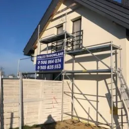 Dom jednorodzinny w Opolu w trakcie prac związanych z elewacją, widoczne rusztowanie i baner reklamowy z numerami telefonów.