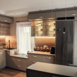 Nowoczesna kuchnia w odcieniach beżu i drewna z oświetleniem LED pod szafkami, szklana witryna z filiżankami i srebrna lodówka.