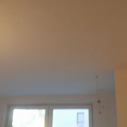 Świeżo pomalowany, jasny sufit w pokoju z oknem, widoczne wystające kable od oświetlenia, co sugeruje prace wykończeniowe.