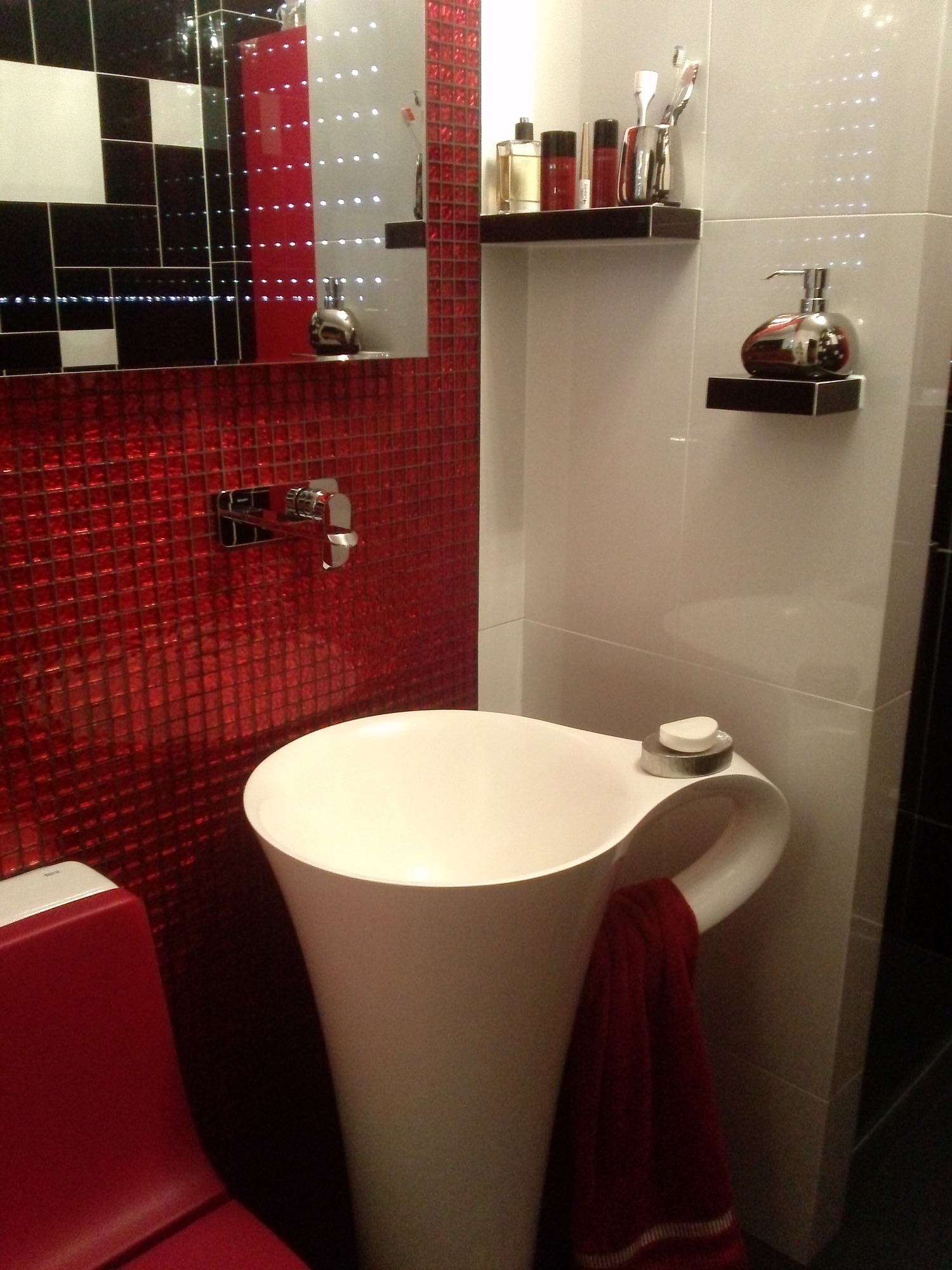 Nowoczesna łazienka z umywalką w kształcie kielicha, czerwonymi płytkami mozaikowymi i czarno-białą ścianą z lustrem.