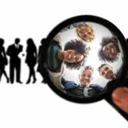 Grupa osób widziana przez lupę, z sylwetkami innych osób w tle. Lupa skupia się na uśmiechniętych twarzach, sugerując pozytywne relacje.