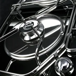 Błyszcząca, chromowana kuchenka gazowa z czarnym szklanym blatem, uchwycona z bliskiej perspektywy, uwydatniająca metaliczne refleksy i minimalistyczny design.