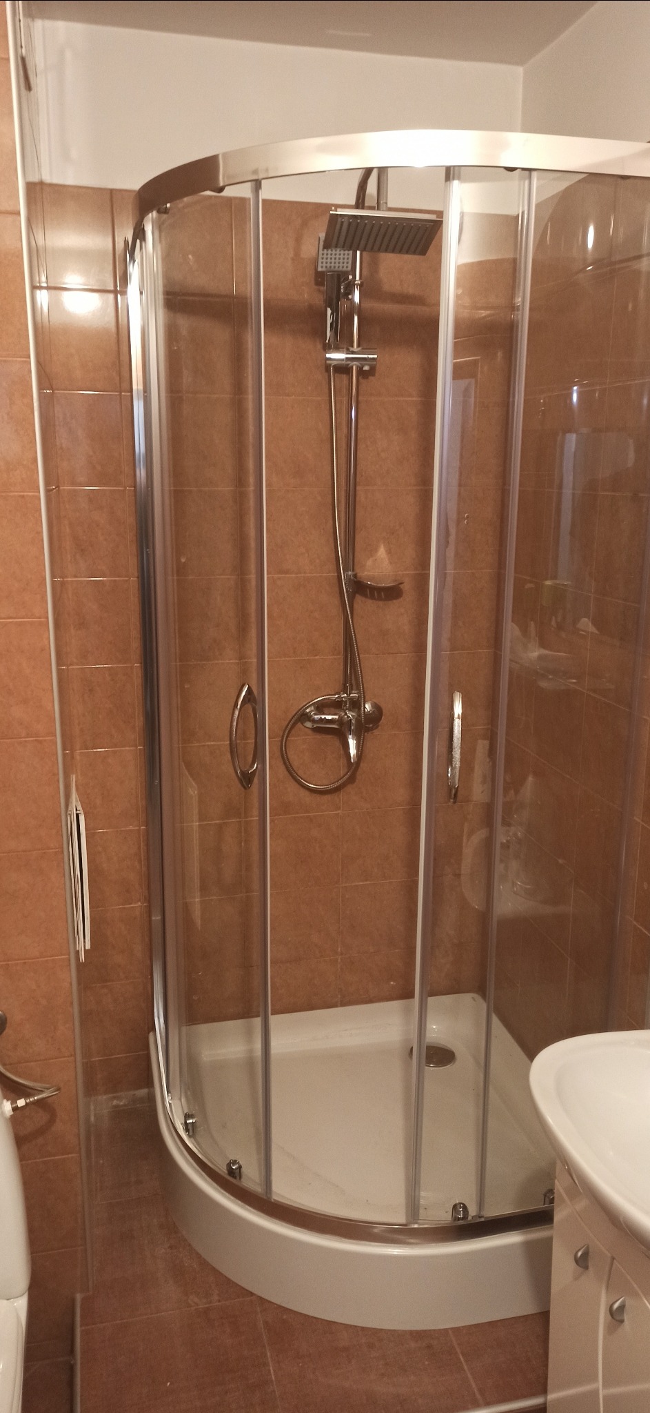 Kabina prysznicowa z deszczownicą i baterią termostatyczną w łazience z brązowymi płytkami.