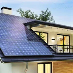 Nowoczesny dom jednorodzinny z panelami słonecznymi na dachu i balkonem z roślinami, widok z dołu w słoneczny dzień.