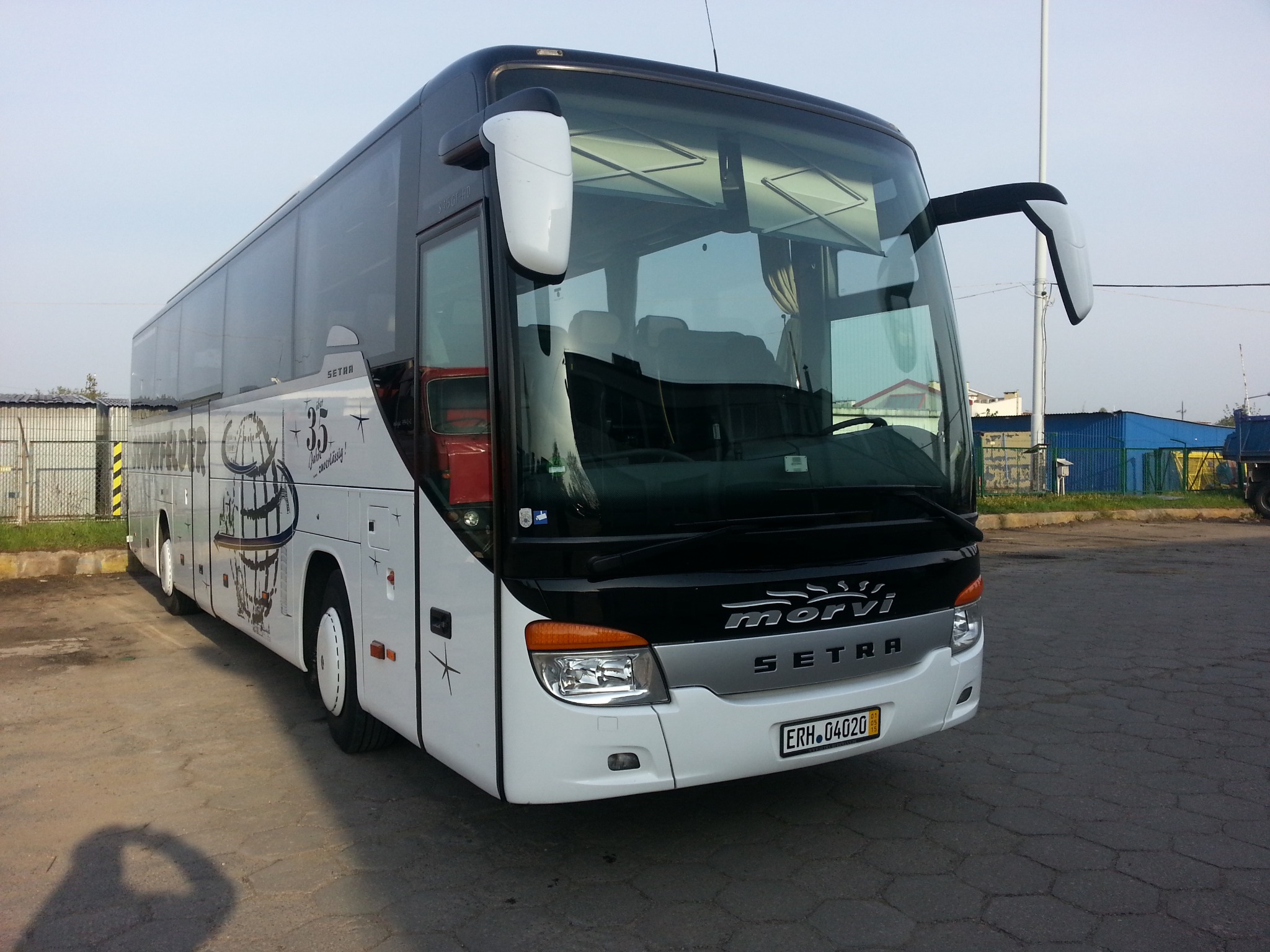 Biało-czarny autobus Setra z grafiką okolicznościową 35-lecia firmy, zaparkowany na betonowym placu, z widocznym numerem rejestracyjnym ERH 04020.