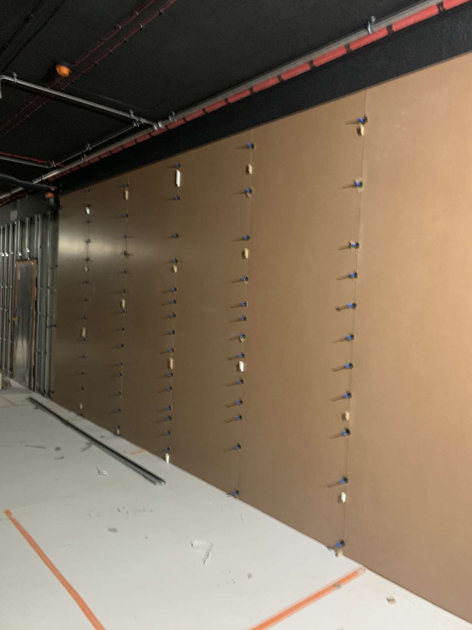 Montaż płyt ściennych w biurze, widoczne kołki i poziomice, przygotowanie do malowania.