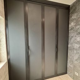 MONSTER - WELD MICHAŁ BERNATOWICZ - Nowoczesna, grafitowa zabudowa szafy wnękowej z metalowymi ramami i matowymi frontami, dopasowana do wnętrza z marmurowymi płytkami na ścianach.