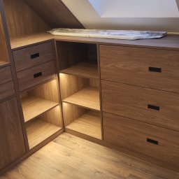 MEBLE Z PASJĄ Emilia Obłąk - Zabudowa pod skosem z drewna z szufladami i otwartymi półkami z podświetleniem LED, widoczny fragment okna dachowego.