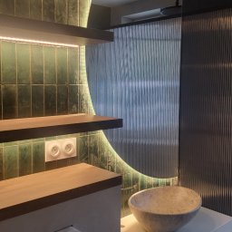 MEBLE Z PASJĄ Emilia Obłąk - Nowoczesna łazienka z zielonymi płytkami, podświetlanymi półkami, umywalką w kształcie misy i szklaną ścianką prysznicową z ryflowanego szkła.