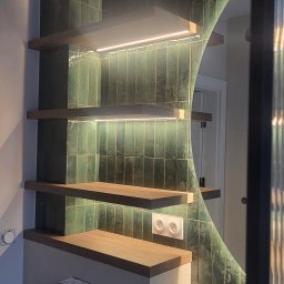 MEBLE Z PASJĄ Emilia Obłąk - Nowoczesna łazienka z zielonymi, pionowymi płytkami, drewnianymi półkami podświetlonymi LED, okrągłym lustrem z podświetleniem i umywalką z kamienia.