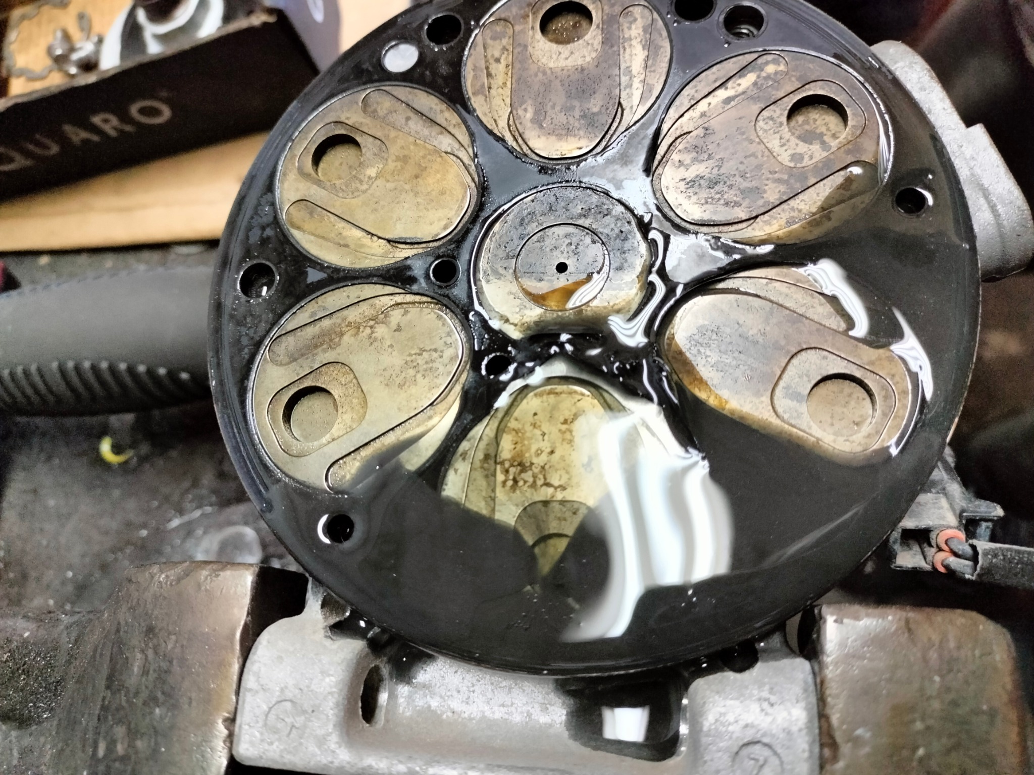 Głowica silnika samochodowego z widocznymi zaworami, zalana olejem, z bliska, podczas naprawy w warsztacie.