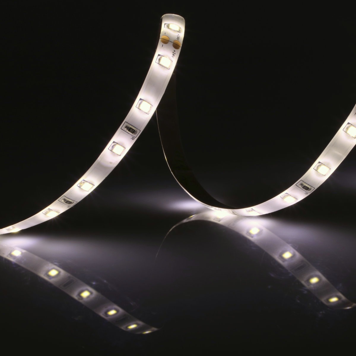 Elastyczna taśma LED z białym światłem na czarnym, błyszczącym tle, z widocznym odbiciem.
