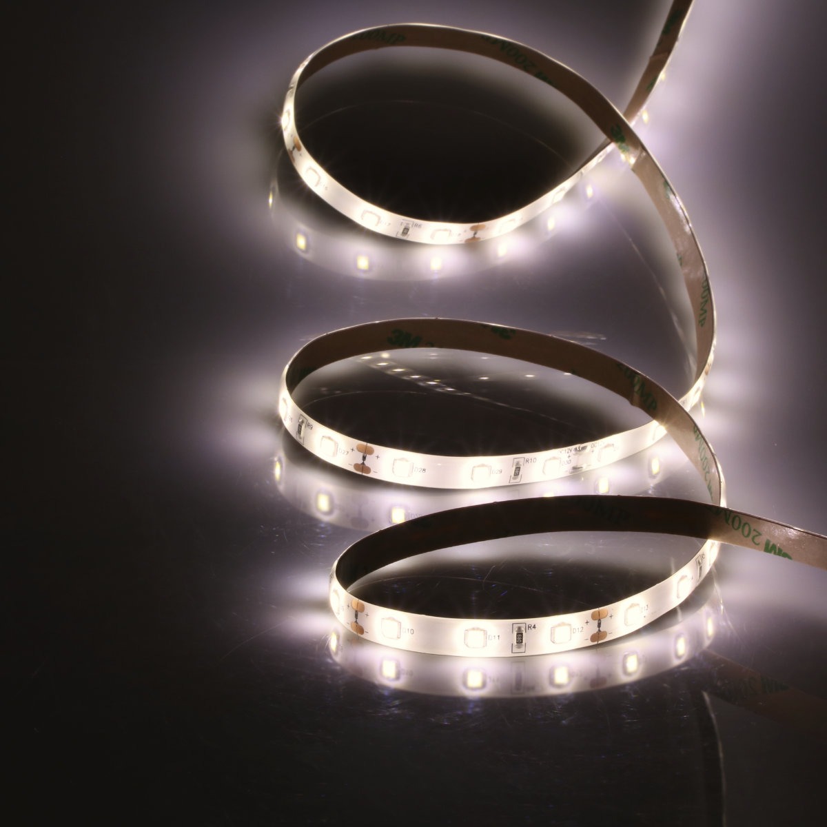 Elastyczna taśma LED z widocznym paskiem samoprzylepnym 3M, ułożona w pętle na błyszczącej powierzchni, emitująca jasne, białe światło.