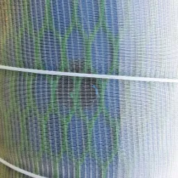 Z bliska widok na perforowaną obudowę studni, zabezpieczoną białymi plastikowymi opaskami, z widocznymi odcieniami niebieskiego i zielonego.