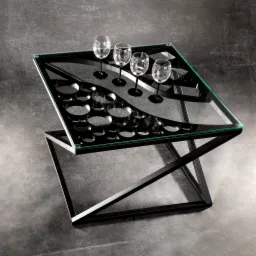 Nowoczesny stolik kawowy z czarną metalową podstawą i szklanym blatem z otworami na kieliszki, na którym stoją cztery kieliszki do wina, na tle szarej ściany.