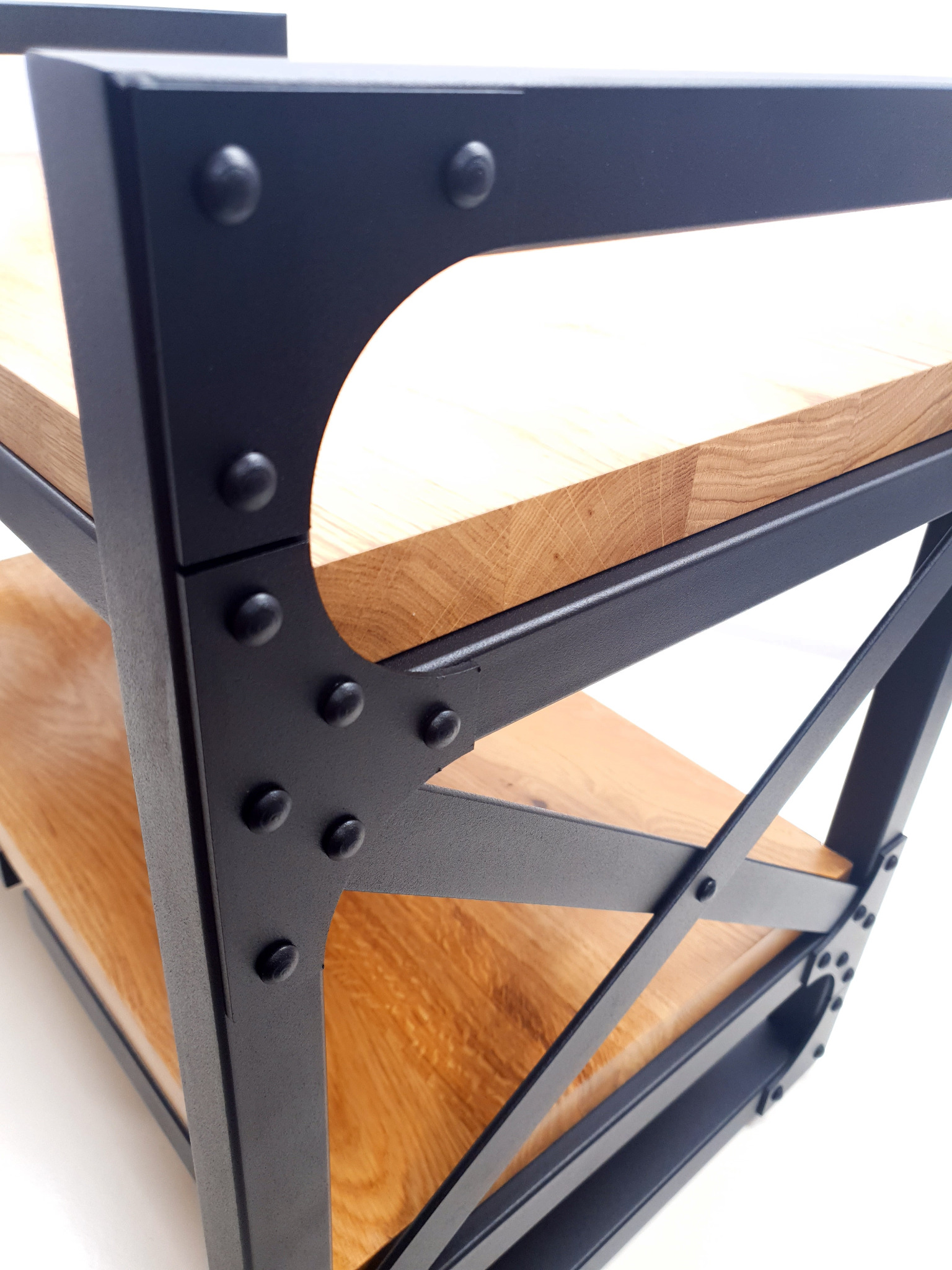 Regał z drewnianymi półkami i czarną, metalową konstrukcją w stylu industrialnym, wykonany w Rusinowicach, z widocznymi nitami łączącymi elementy.