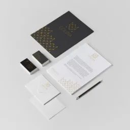 Komplet identyfikacji wizualnej firmy Goldia: wizytówki, papier firmowy, koperta i teczka, utrzymane w kolorystyce czerni, bieli i złota z geometrycznym motywem korony.