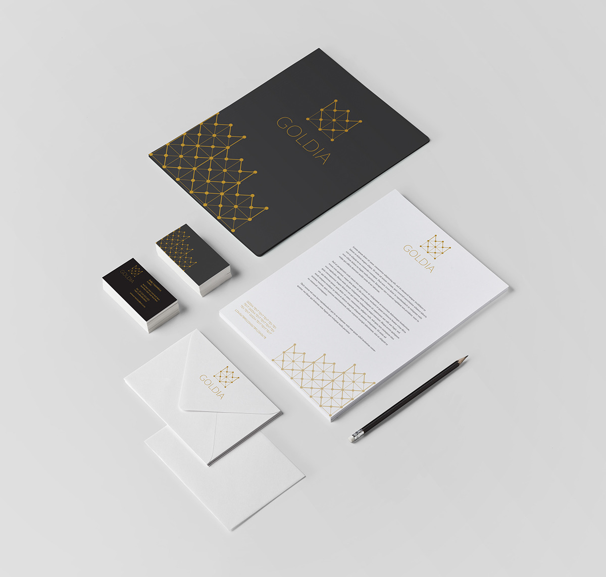 Komplet identyfikacji wizualnej firmy Goldia: wizytówki, papier firmowy, koperta i teczka, utrzymane w kolorystyce czerni, bieli i złota z geometrycznym motywem korony.