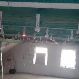 Metalowe uchwyty z czerwoną diodą LED, zamocowane do drewnianych belek stropowych poddasza, wyznaczające poziom przyszłej izolacji, widoczne okna i podnośnik do płyt gipsowych.