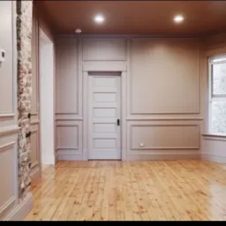 Pokój po remoncie z drewnianą podłogą, ścianami w odcieniach beżu z dekoracyjnymi panelami, odsłoniętym fragmentem ceglanej ściany i białymi drzwiami.