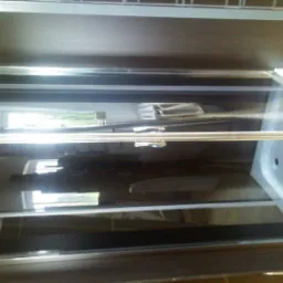 Zaokrąglona kabina prysznicowa z chromowanymi detalami i przesuwnymi drzwiami, widoczna z boku w słabym oświetleniu.