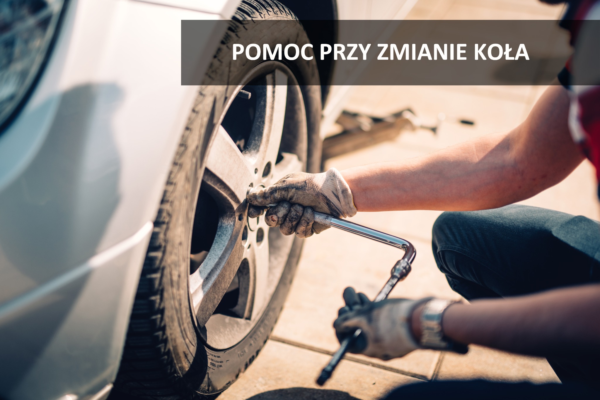 Mechanik w rękawicach roboczych odkręca śruby koła samochodu za pomocą klucza nasadowego.