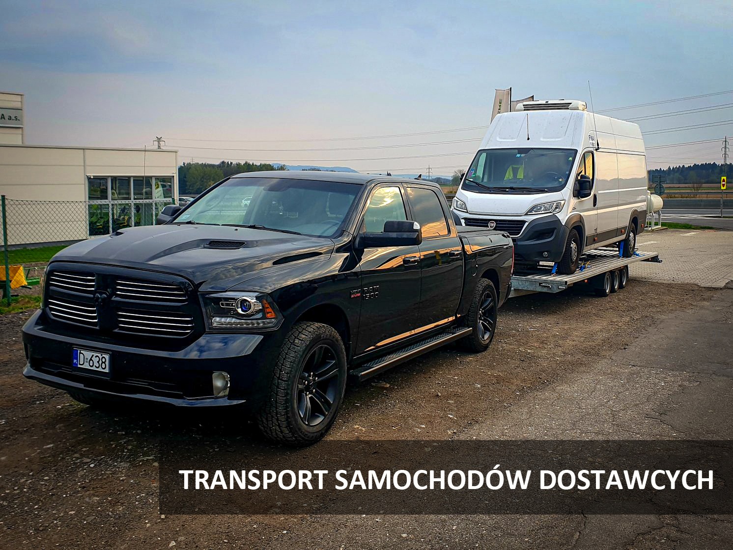 Czarny pickup RAM z lawetą przewożącą biały samochód dostawczy typu furgon chłodnia, widok z przodu, tablica rejestracyjna D-638
